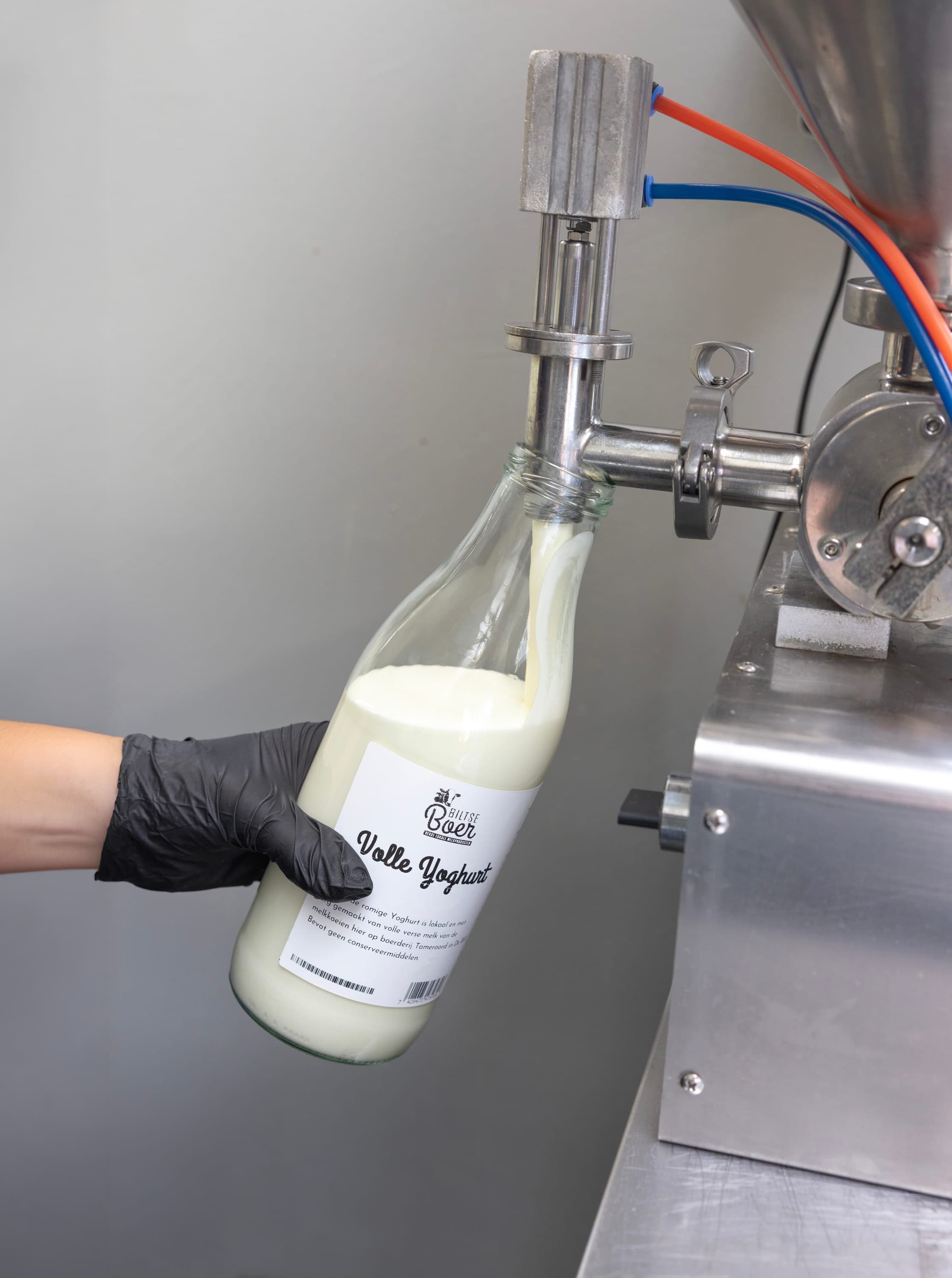Een glazen fles volle yoghurt wordt afgevuld in de zuivelkeuken