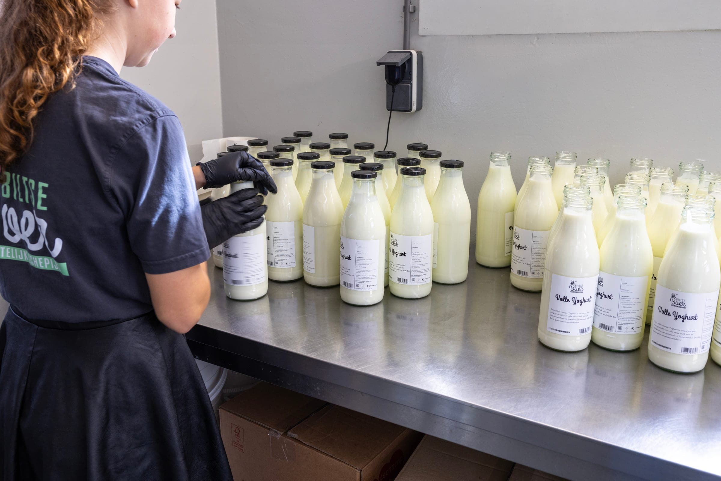A member of staff caps the glass bottles of fresh yoghurt in the dairy kitchen