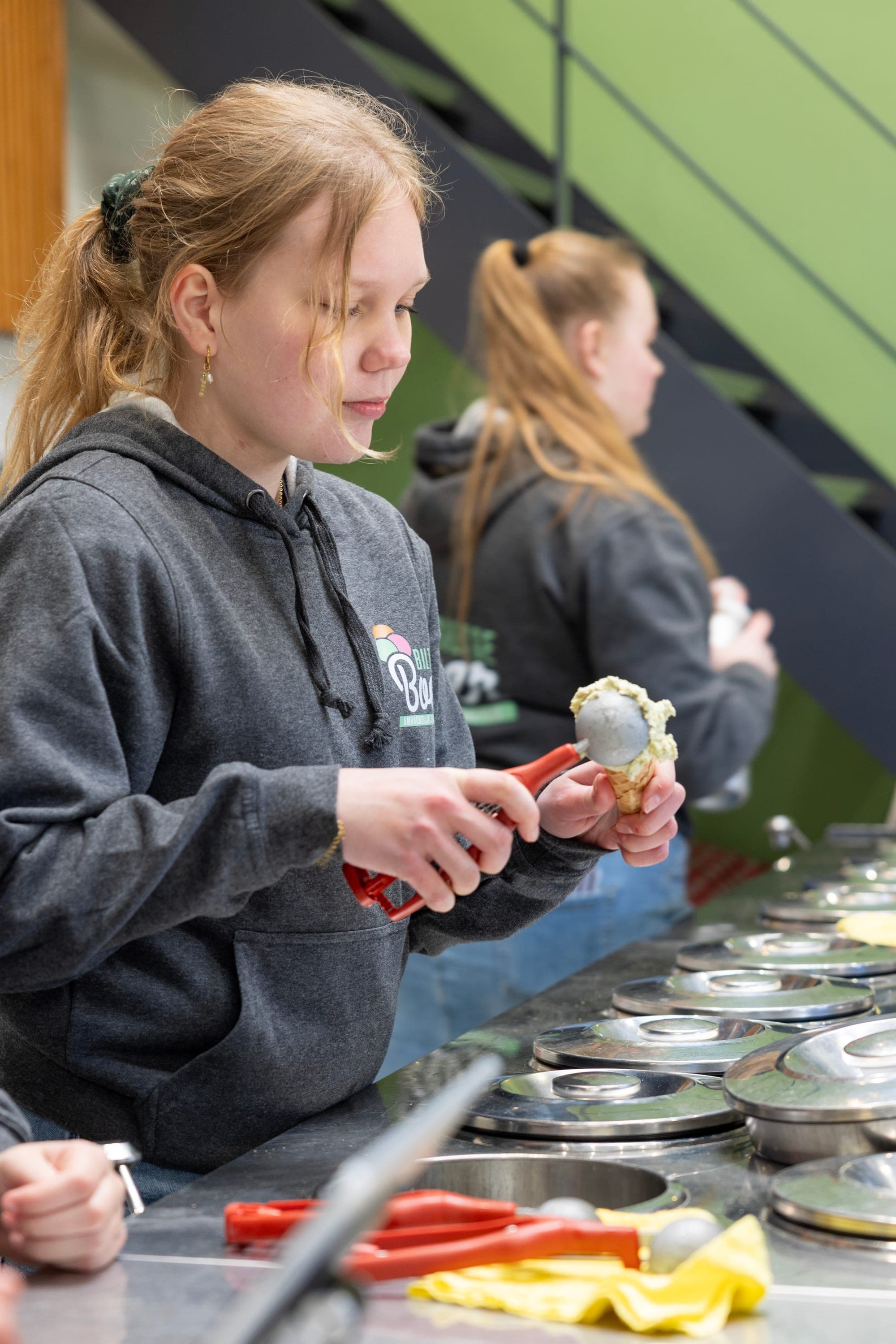 A member of staff scoops ice cream onto a cone in the parlour